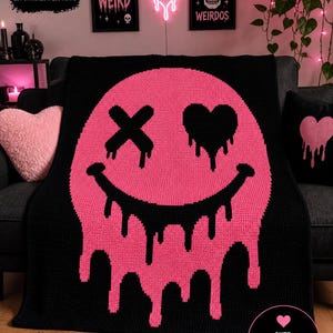 May include: Black and pink throw blanket with a smiley face design. The blanket measures 36 inches by 54 inches. The image also shows decorative pillows, wall art, and a neon heart.