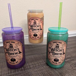 May include: Three colorful tumblers with lids and straws. The tumblers are purple, tan, and green, each with a matching lid and straw. The labels read "Witch's Brew" and "Salem, MA."