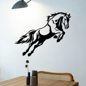May include: Black silhouette of a horse leaping in mid-air, with its mane and tail flowing behind it. The horse is mounted on a white wall.