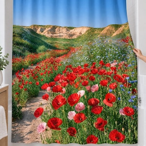 Red poppy wildflower shower curtain over a bathtub in a white-tiled bathroom: red and pink poppies and blue wildflowers line a sandy path toward pale hills under a wide blue sky; a hand pulls back the right edge.