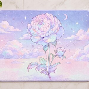May include: A rectangular bath mat featuring a pastel-coloured illustration of a large peony flower and a smaller bud. The background displays a dreamy sky with soft pink and purple clouds, a crescent moon, and scattered four-pointed stars.