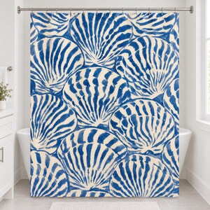 Straight-on front view of the blue scallop shell shower curtain hanging from a chrome rod over a white tub.