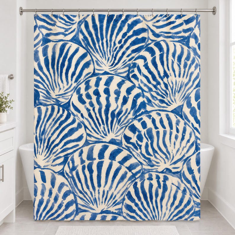 Straight-on front view of the blue scallop shell shower curtain hanging from a chrome rod over a white tub.