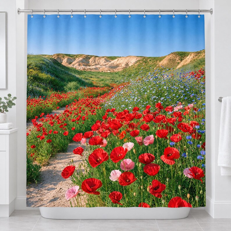 Straight-on view of the whole poppy wildflower shower curtain hanging in a white bathroom, showing the poppy field, blue wildflowers, sandy path, pale eroded hills and clear blue sky.