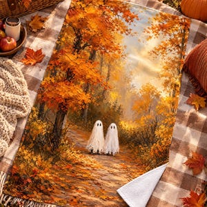 Pu&ograve; includere: Una coperta rettangolare con una stampa in stile pittura a olio raffigurante due fantasmi bianchi su un sentiero in un bosco pieno di vivaci foglie autunnali arancioni e gialle. La coperta ha un lato inferiore bianco e un angolo ripiegato.