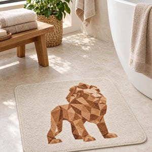 May include: A rectangular bath mat in a light beige colour featuring a geometric lion design in shades of brown. The lion is composed of various triangular and polygonal shapes, creating a faceted appearance on the textured surface of the mat.