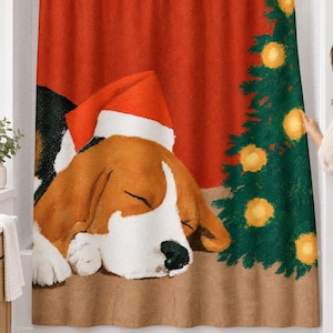 Shower curtain with a painted beagle asleep in a red-and-white Santa hat beside a small Christmas tree with glowing lights on a red wall, hanging on a chrome rod in a white bathroom.