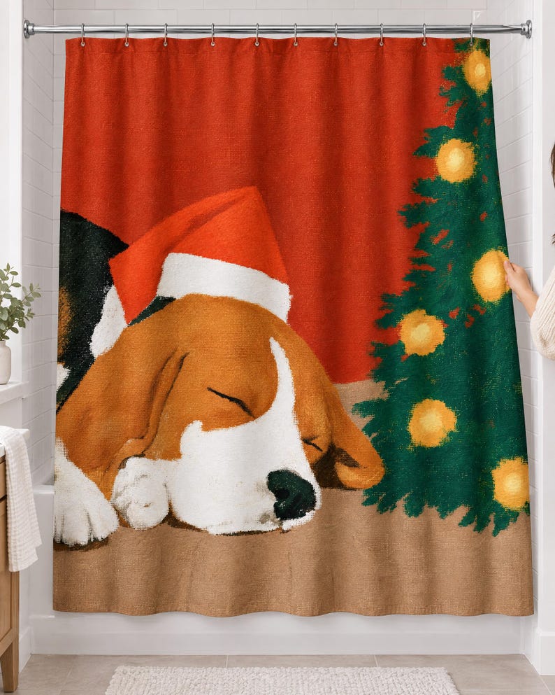 Shower curtain with a painted beagle asleep in a red-and-white Santa hat beside a small Christmas tree with glowing lights on a red wall, hanging on a chrome rod in a white bathroom.