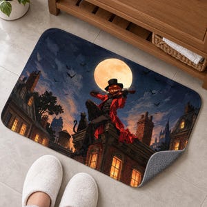 Bath mat with a pumpkin-head violinist, black cat, bats and glowing brick townhouses under a full moon, on a tiled floor by a wooden vanity; feet in white slippers rest nearby and one corner flips up to show the gray anti-slip back.