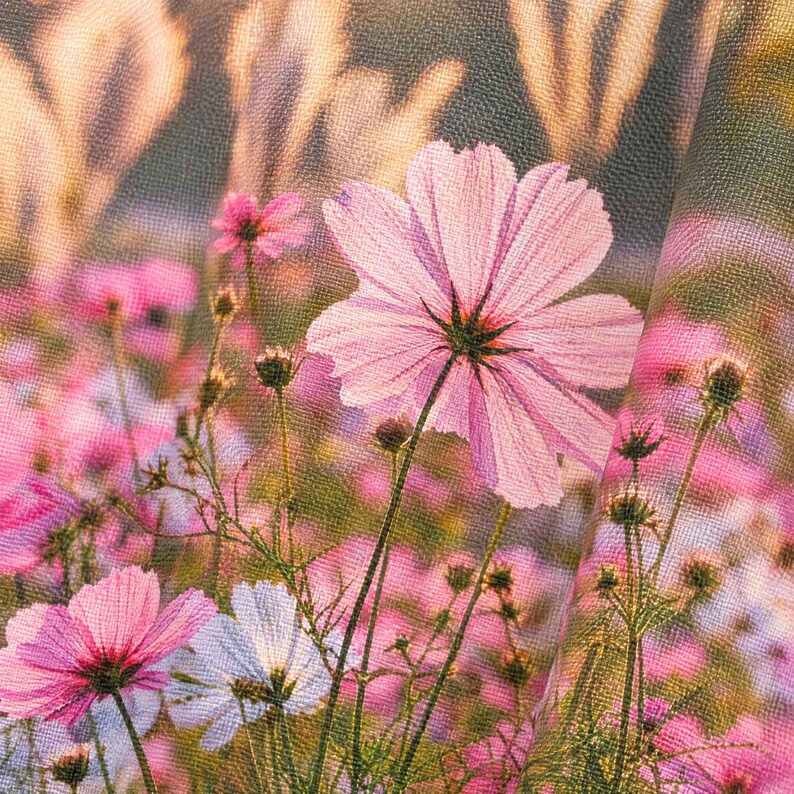 K&ouml;nnte beinhalten: Ein Stoff mit einem Druckmuster aus rosa und wei&szlig;en Kosmosbl&uuml;ten mit gr&uuml;nen Stielen und Bl&auml;ttern. Das Material weist eine sichtbare Webstruktur auf und zeigt ein Feld mit bl&uuml;henden Blumen in verschiedenen Wachstumsstadien.