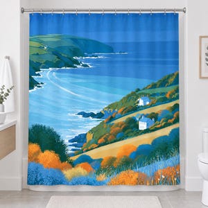 Straight-on view of the whole retro sea cliff shower curtain hanging in a white bathroom, showing the blue sky, distant headland, curving shoreline, two cottages and bright orange and blue shrubs.