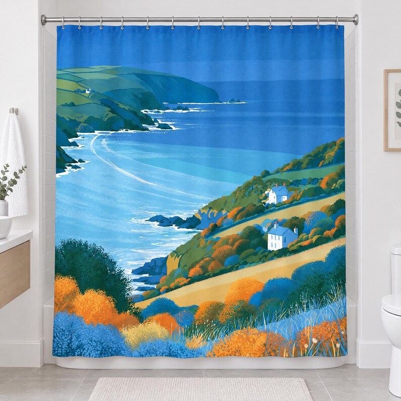 Straight-on view of the whole retro sea cliff shower curtain hanging in a white bathroom, showing the blue sky, distant headland, curving shoreline, two cottages and bright orange and blue shrubs.