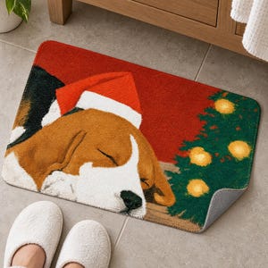 Sleeping beagle Santa hat bath mat in front of a wood vanity, one corner turned up to show the gray anti-slip back, with white slippers below.