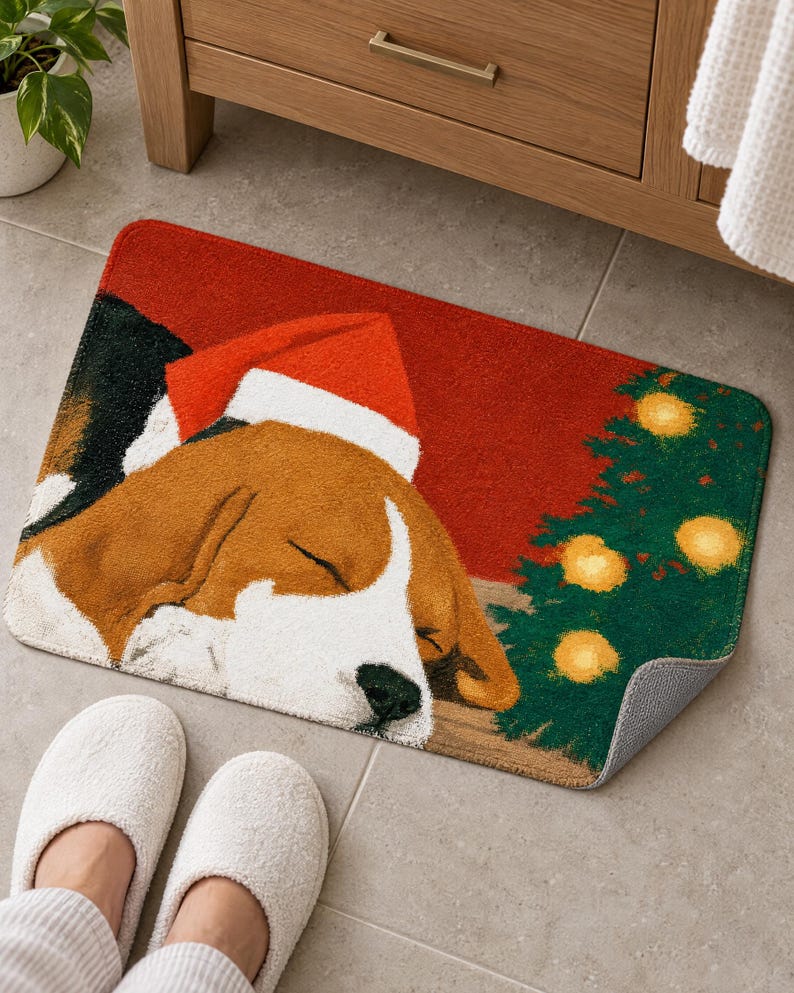 Sleeping beagle Santa hat bath mat in front of a wood vanity, one corner turned up to show the gray anti-slip back, with white slippers below.