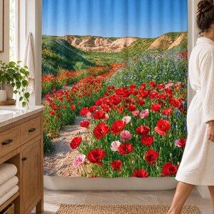 Wider view of a sunny bathroom with the red poppy wildflower shower curtain closed across the tub, a wooden vanity and plant to the left and a woman in a white robe walking past barefoot.