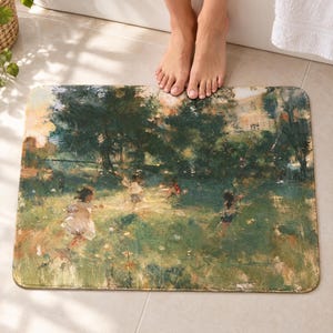 Impressionist garden bath mat on a tiled floor in front of a white bathtub: children in pale clothes play in a sunny green meadow under dark trees, painted in loose brushstrokes; bare toes rest at the top edge nearest the tub.