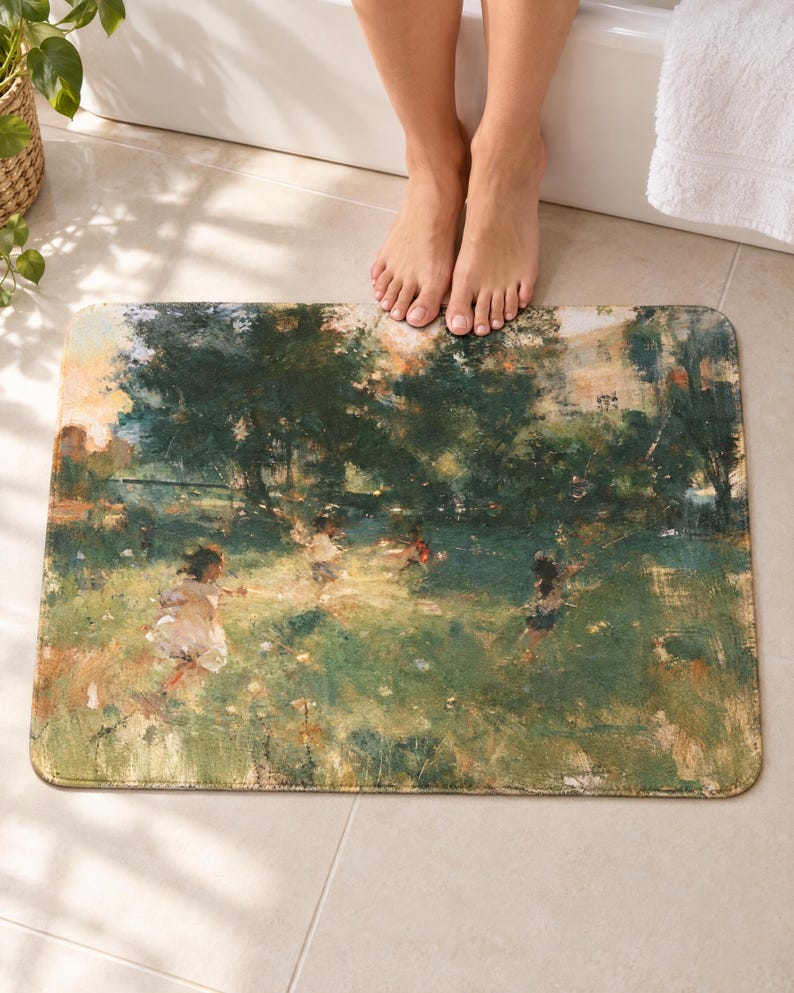 Impressionist garden bath mat on a tiled floor in front of a white bathtub: children in pale clothes play in a sunny green meadow under dark trees, painted in loose brushstrokes; bare toes rest at the top edge nearest the tub.