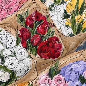 Pu&ograve; includere: Una stampa su tessuto che raffigura diversi bouquet di fiori dipinti a mano avvolti in carta marrone. Il motivo include grappoli di rose rosse, rose bianche, fiori gialli e ortensie viola, tutti accentuati da foglie e steli verdi.