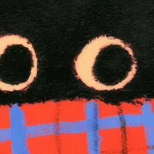 Close-up of the bath mat's print: the cat's two round cream-ringed eyes above a red-orange plaid scarf with blue stripes.