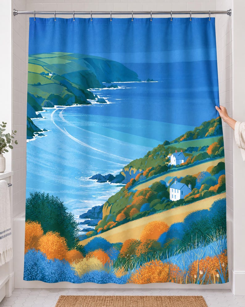 Retro sea cliff shower curtain over a bathtub in a white-tiled bathroom: a deep blue bay curves past green headlands, two white cottages and orange and blue shrubs in a flat graphic style; a hand pulls back the right edge.