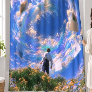 Surreal swirling sky shower curtain over a bathtub in a white-tiled bathroom: a man in a white shirt stands in a wildflower meadow beneath a huge spiral of rainbow-tinted clouds and floating pages; a woman pulls back the right edge.