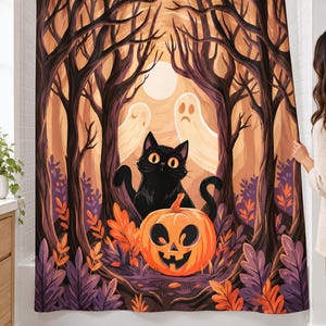 Black cat ghost moon shower curtain hanging over a bathtub in a white-tiled bathroom, showing a jack-o'-lantern, bare twisted trees and autumn leaves; a woman's hand pulls back the right edge.