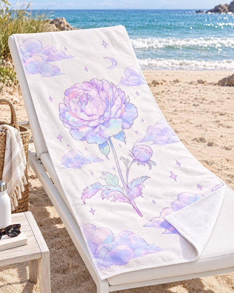 May include: A white rectangular beach towel featuring a large, central illustration of a blooming peony flower in shades of pastel purple, pink, and blue, surrounded by soft clouds, small stars, and a crescent moon graphic.