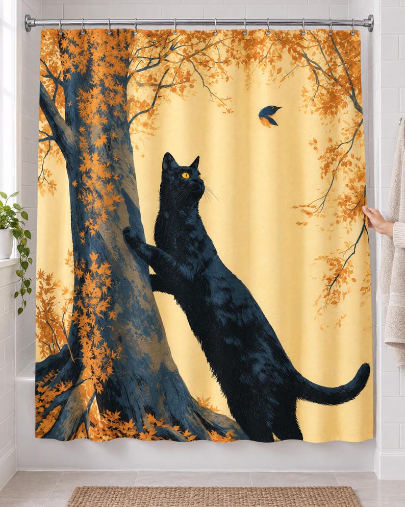 Autumn tree cat shower curtain over a bathtub in a white-tiled bathroom: a cat reaches up a big tree trunk toward a small bird among orange leaves, its body running down to the bottom hem; a hand pulls back the right edge.
