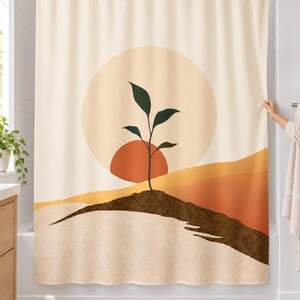 Boho seedling sun shower curtain over a bathtub in a white-tiled bathroom: a dark green sprout on a brown soil ridge before a terracotta half sun and pale circle, with ochre and rust hills on cream; a hand pulls back the right edge.