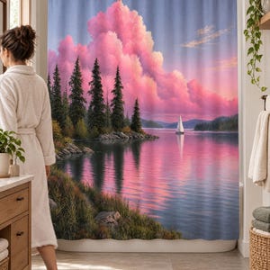 Wider view of a bright bathroom with the pine lake sailboat shower curtain closed across the tub and a woman in a white robe standing barefoot in front of it, partly hiding the pines, beside a wooden vanity.