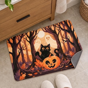 Halloween black cat bath mat on a tiled floor beside a wooden vanity, with a person in white slippers standing at its edge; one corner is flipped up to show the plain gray anti-slip back.