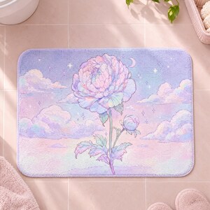 May include: A rectangular bath mat featuring a soft pastel illustration of a large blooming peony and a smaller bud centred against a dreamy sky filled with fluffy clouds, twinkling stars, and a crescent moon in shades of lavender, pink, and blue.