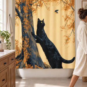 Wider view of a sunny bathroom with the autumn tree cat shower curtain closed across the tub, a wooden vanity and plant to the left and a woman in a white robe walking past barefoot.