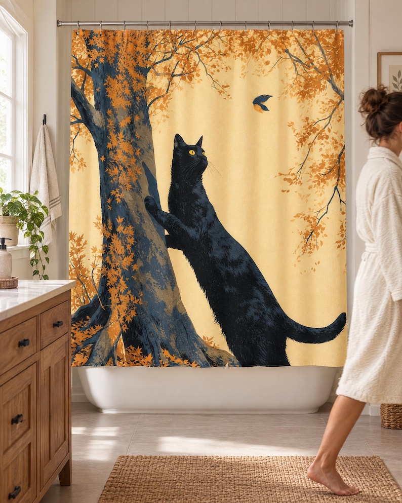 Wider view of a sunny bathroom with the autumn tree cat shower curtain closed across the tub, a wooden vanity and plant to the left and a woman in a white robe walking past barefoot.