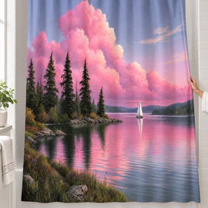 Pine lake sailboat shower curtain over a bathtub in a white-tiled bathroom: tall pines on a rocky shore, a white sailboat and towering pink clouds reflected in a calm blue lake; a hand pulls back the right edge.