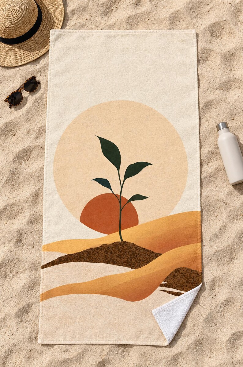 Top-down view of the whole boho sun seedling beach towel laid flat on sand, with plain cream space above the sun and a second small soil mound at the right, plus a straw hat, sunglasses and a white water bottle.