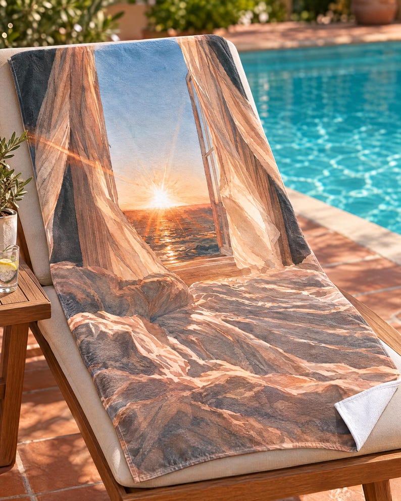 May include: A rectangular beach towel featuring a printed image of an open window looking out onto a sunset over the ocean. The design includes sheer white curtains blowing inward, a bright golden sun on the horizon, and rocky terrain in the foreground.
