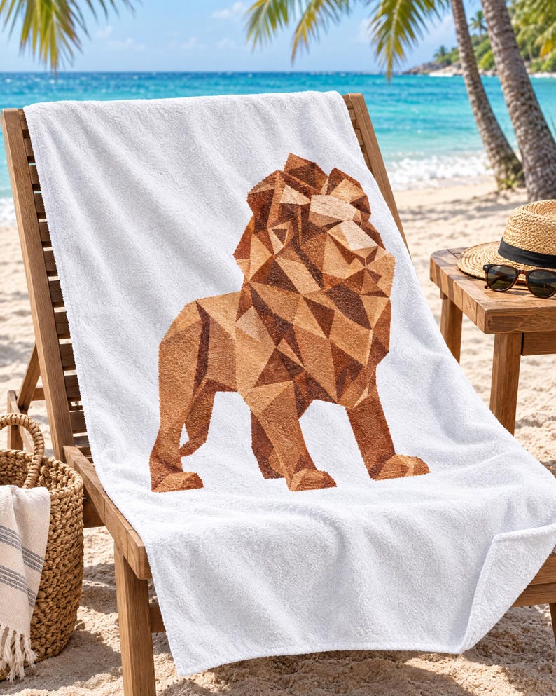 May include: A white beach towel featuring a large, geometric lion graphic composed of various shades of brown and tan triangles. The lion is depicted in a standing profile view, centered on the soft, textured fabric of the rectangular towel.