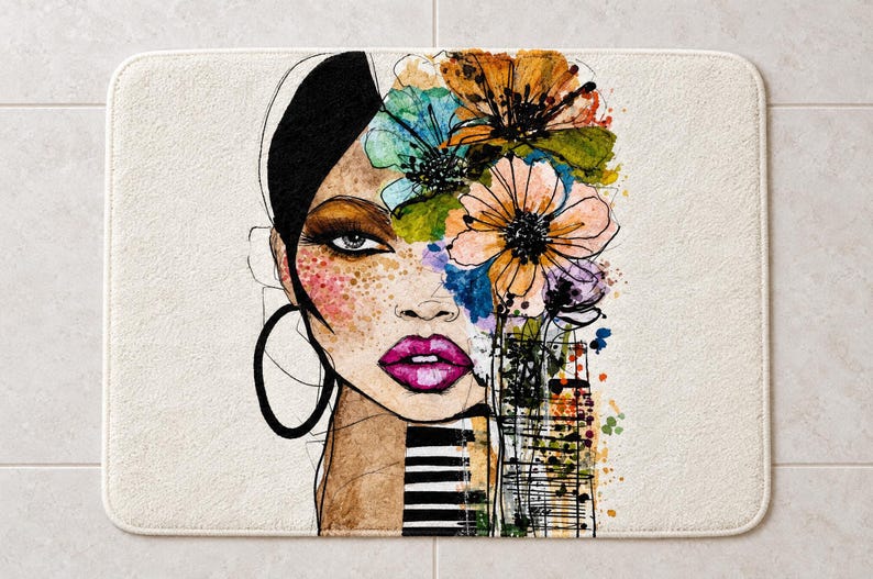 May include: A rectangular bath mat featuring a stylized illustration of a face with black hair, large hoop earrings, and bright pink lips. The design incorporates vibrant watercolor flowers in orange, blue, and green, with black ink line details.
