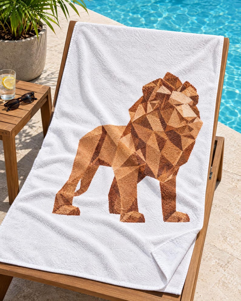 May include: A white rectangular beach towel featuring a large, centered graphic of a lion rendered in a geometric, low-poly style. The lion figure is composed of various shades of brown and tan, creating a faceted, angular appearance on the fabric.