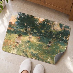 Painterly garden bath mat with children running through a meadow on a tiled floor by a wooden vanity; feet in white slippers rest on the tile in front and one corner flips up to show the gray anti-slip back.