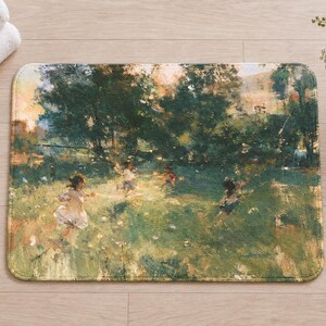 Overhead view of the whole impressionist garden bath mat on a light wood floor, with rolled white towels, a lit candle and a small white vase of daisies and purple wildflowers beside it.