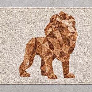 May include: A rectangular bath mat with a cream-coloured textured surface featuring a geometric lion illustration in shades of brown. The lion is composed of various triangular shapes, creating a faceted appearance against the light background.