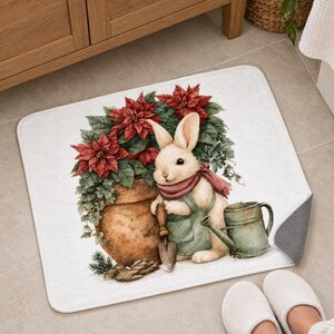 Poinsettia bunny bath mat in front of a wood vanity, one corner turned up to show the gray anti-slip back, with white slippers below.