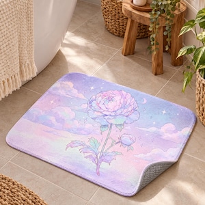 May include: A rectangular bath mat featuring a pastel-coloured illustration of a large blooming peony flower set against a dreamy sky filled with soft pink and purple clouds, twinkling stars, and a crescent moon, with a textured grey non-slip backing.