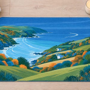 Overhead view of the whole cliffside cottage bath mat on a light wood floor, with rolled white towels, a lit candle and a small glass vase of wildflowers beside it.