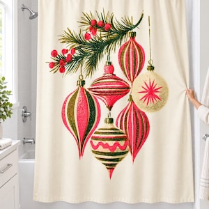 Vintage ornament shower curtain hanging over a bathtub in a white-tiled bathroom: six large striped pink, olive and cream Christmas baubles hang from a pine sprig with red berries; a hand pulls back the right edge.