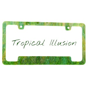 May include: A rectangular license plate frame with a green and yellow marbled design. The text "Tropical Illusion" is written in green cursive script across the center of the frame. The frame has four mounting holes.