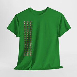 May include: A green t-shirt featuring a vertical pattern of colorful fleur-de-lis symbols. The fleur-de-lis design includes purple, yellow, green, and blue colors. The shirt is made of a soft material.