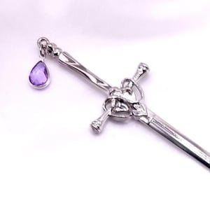 May include: A silver sword with a heart-shaped handle and a purple gemstone charm. The sword is about 10 inches long.